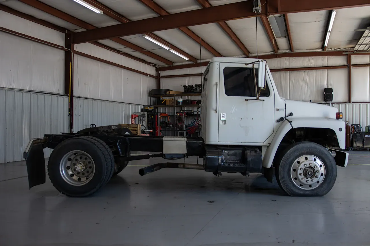 Truck repair with a heavy-duty cab and chassis positioned inside a service bay for maintenance.