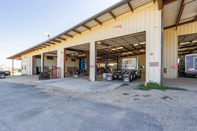 Heavy-duty truck repair facility with open service bays and commercial trucks undergoing maintenance.