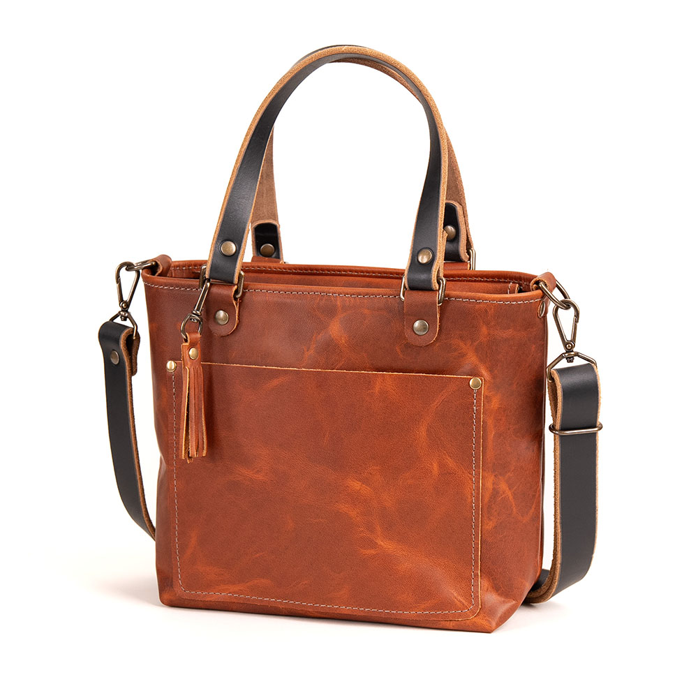 Brown leather bag with brass hardware and straps on a white background