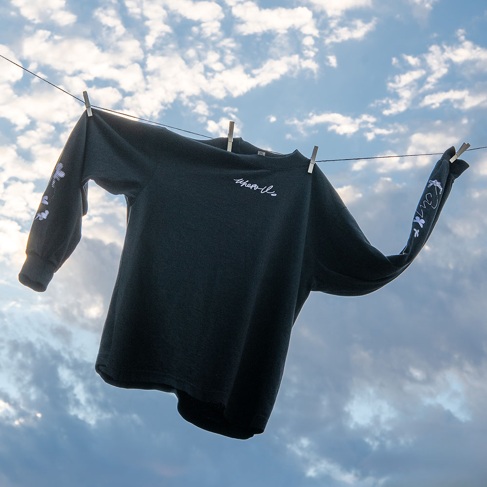 Black long sleeve shirt pinned to a wire with clouds as a background