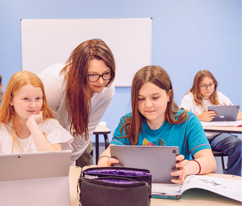 Une professeure et deux élèves regardant une tablette