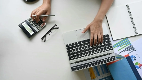 person working on a laptop and calculator