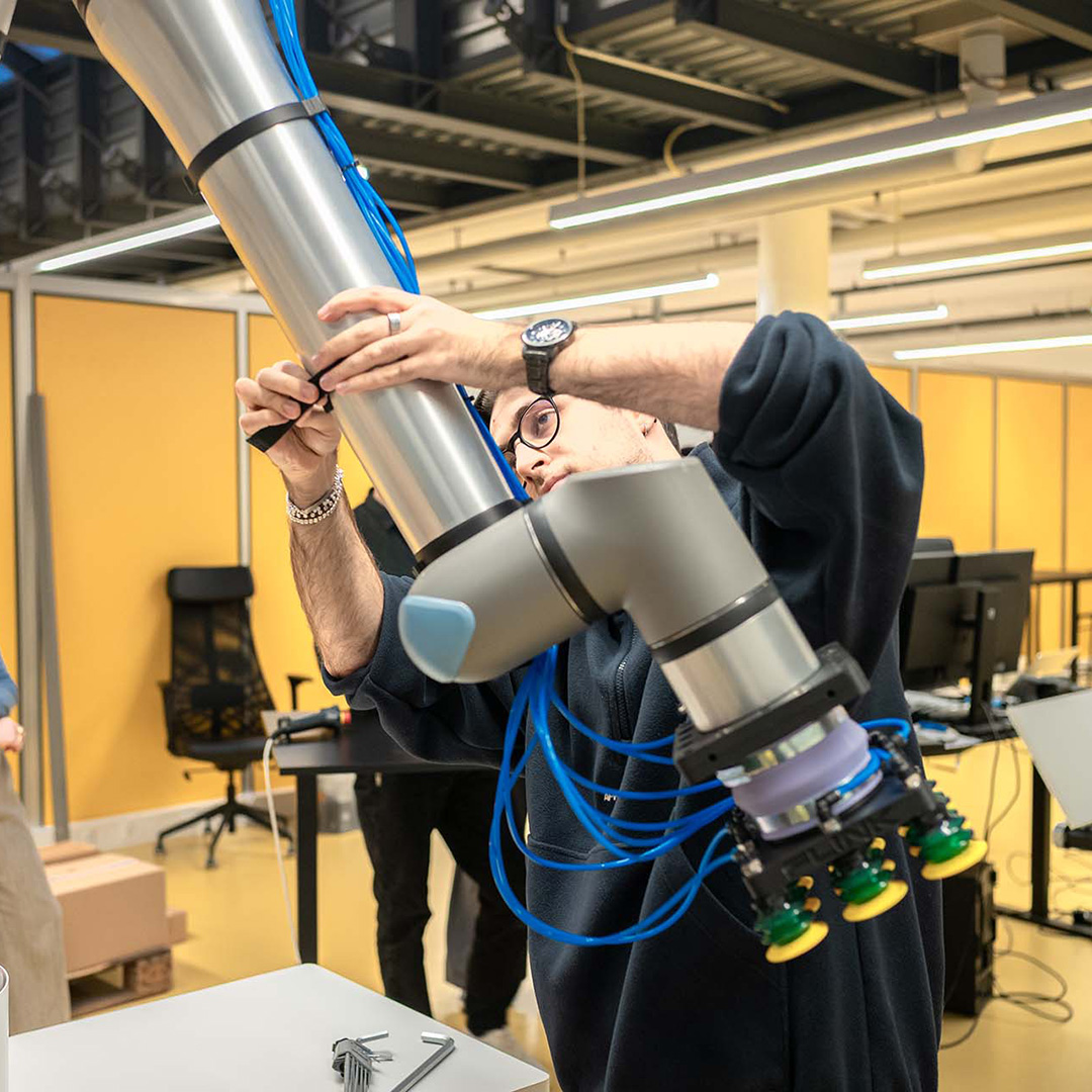 Flink robotics engineer adjusting a robot arm.
