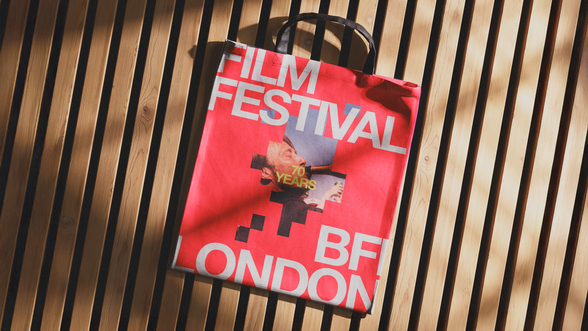 Red tote bag with 'FILM FESTIVAL LONDON' and '70 YEARS' text on wooden slatted surface.