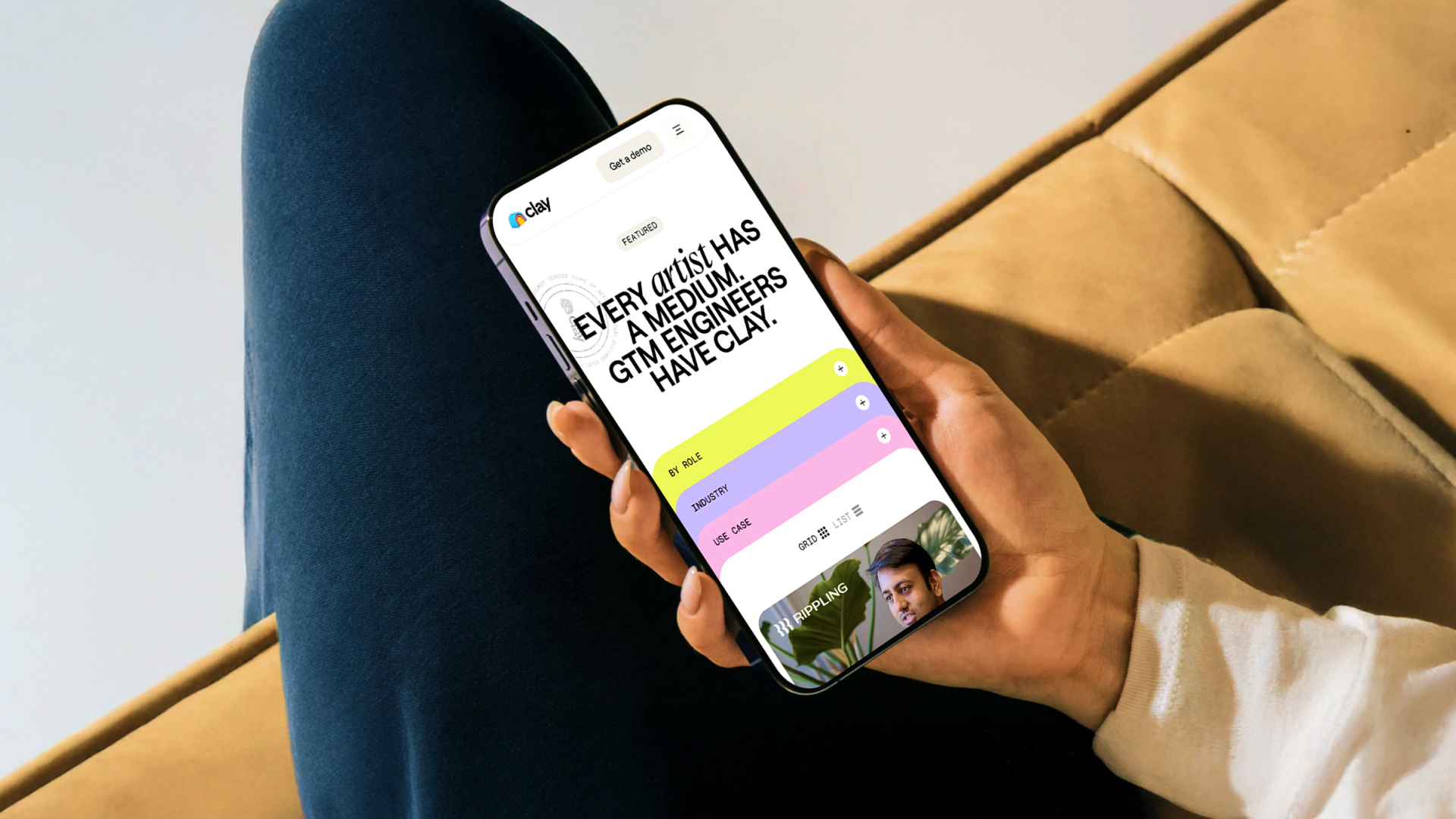 Person holding smartphone showing Clay website with a headline and colorful menu options.