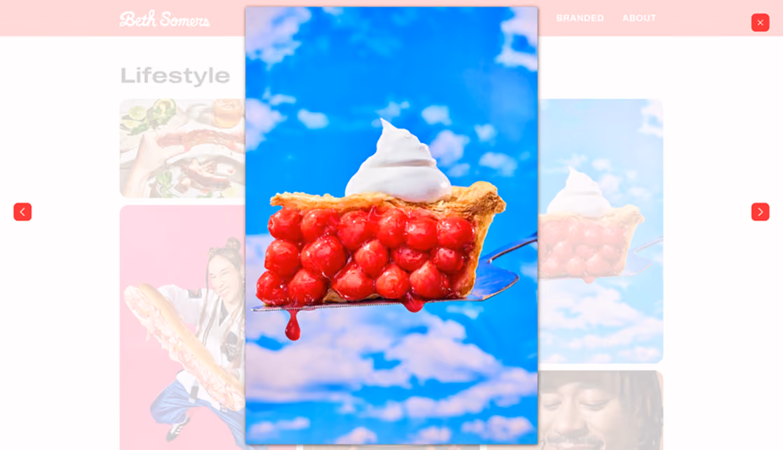 Screenshot of lightbox functionality on the Lifestyle gallery page shows a fullscreen view of a photo of a whipped-cream-topped slice of cherry pie against a blue sky background with clouds. Buttons show forward and backward arrows as well as an x to close the lightbox.