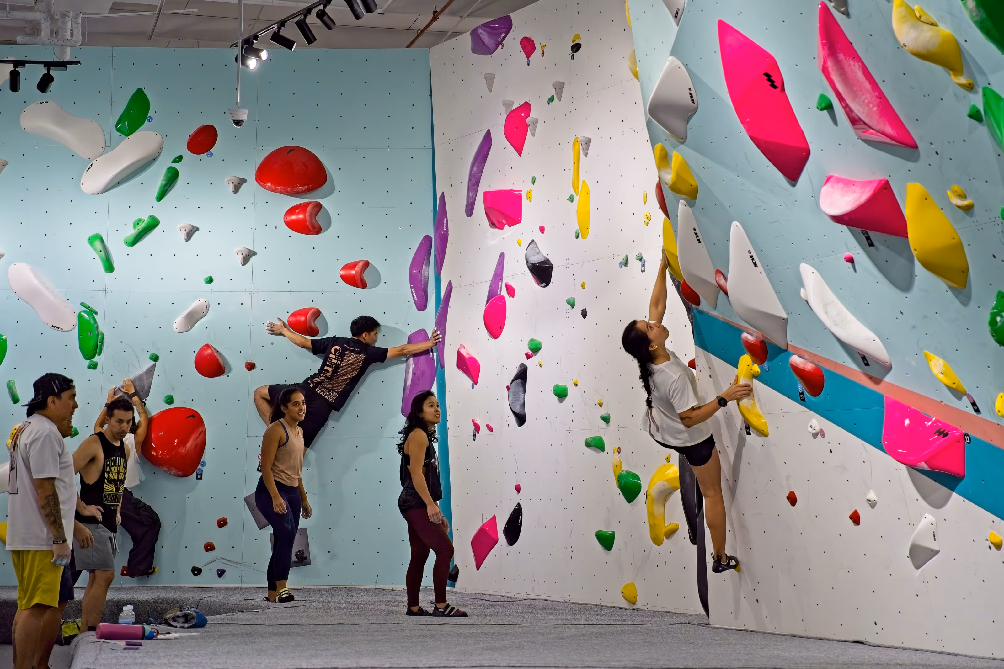 A group of climbers cheering on a female climbing trying a route on an overhang.