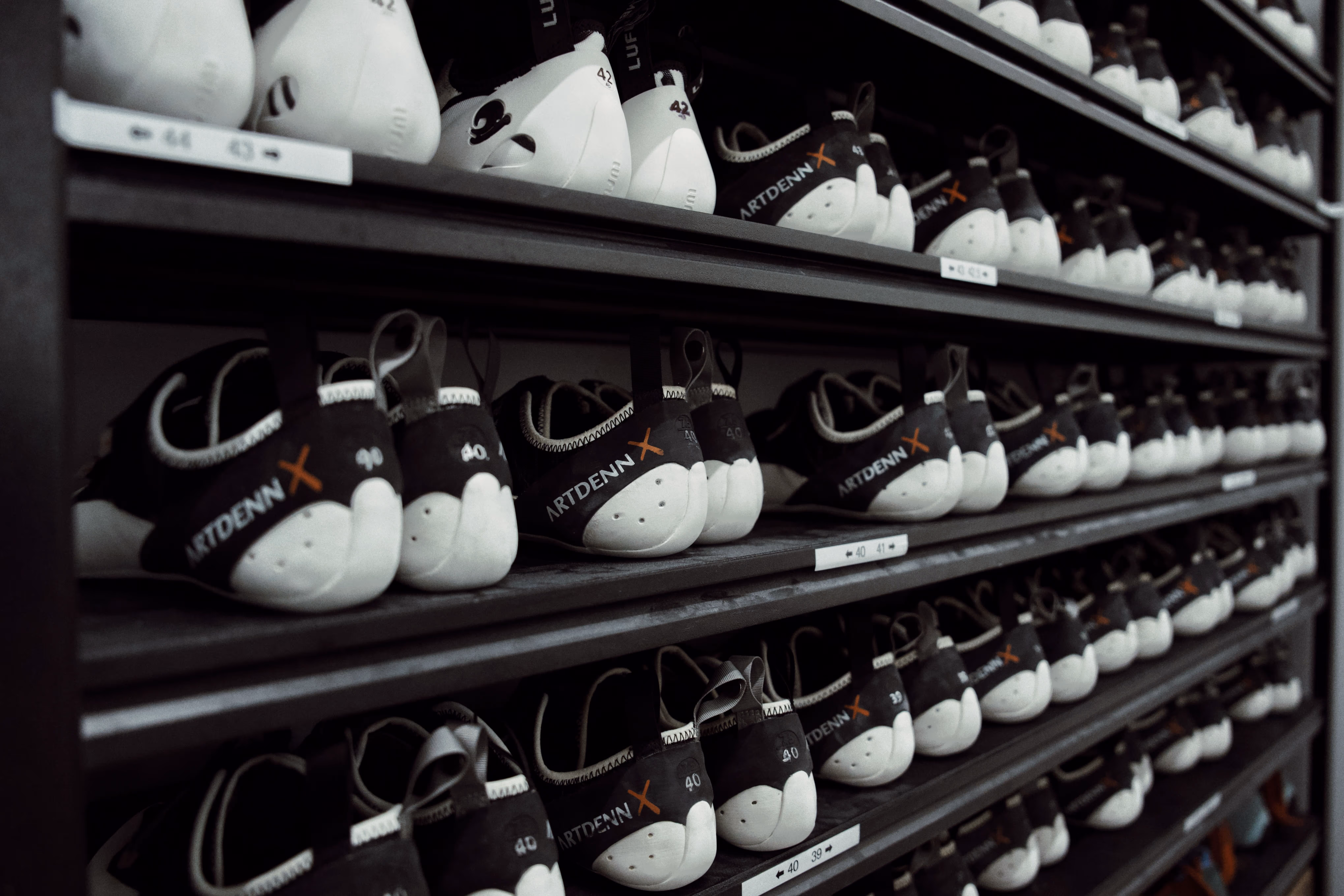 Shelves filled with black and white rental climbing shoes.