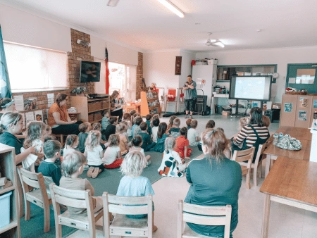A group of people sitting in a room with a projector screen.