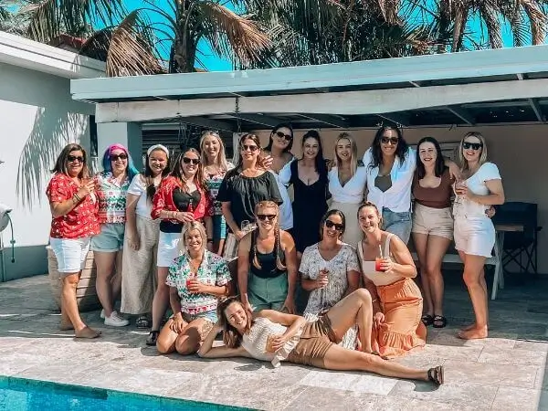 A group of women standing and sitting next to a pool.