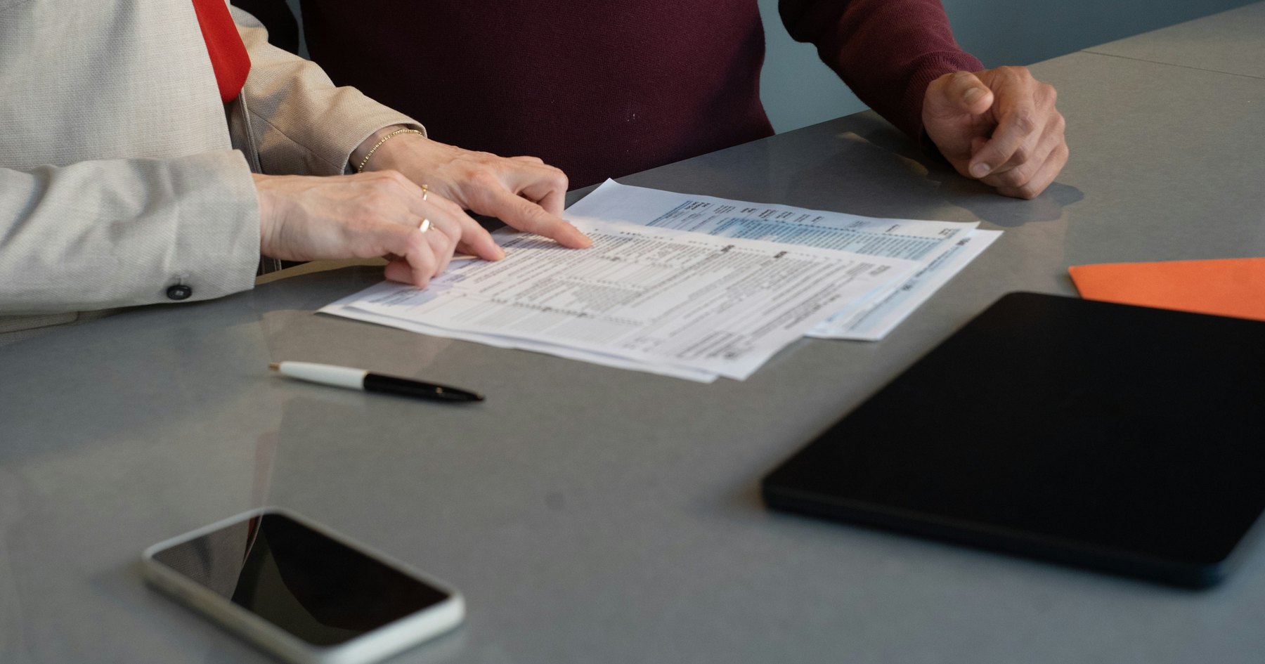 Two people reviewing vendor proposal documents at a meeting table