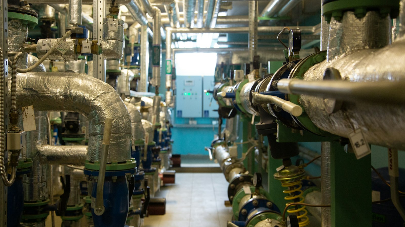Commercial building plant room with insulated pipework, tagged valves and control panels