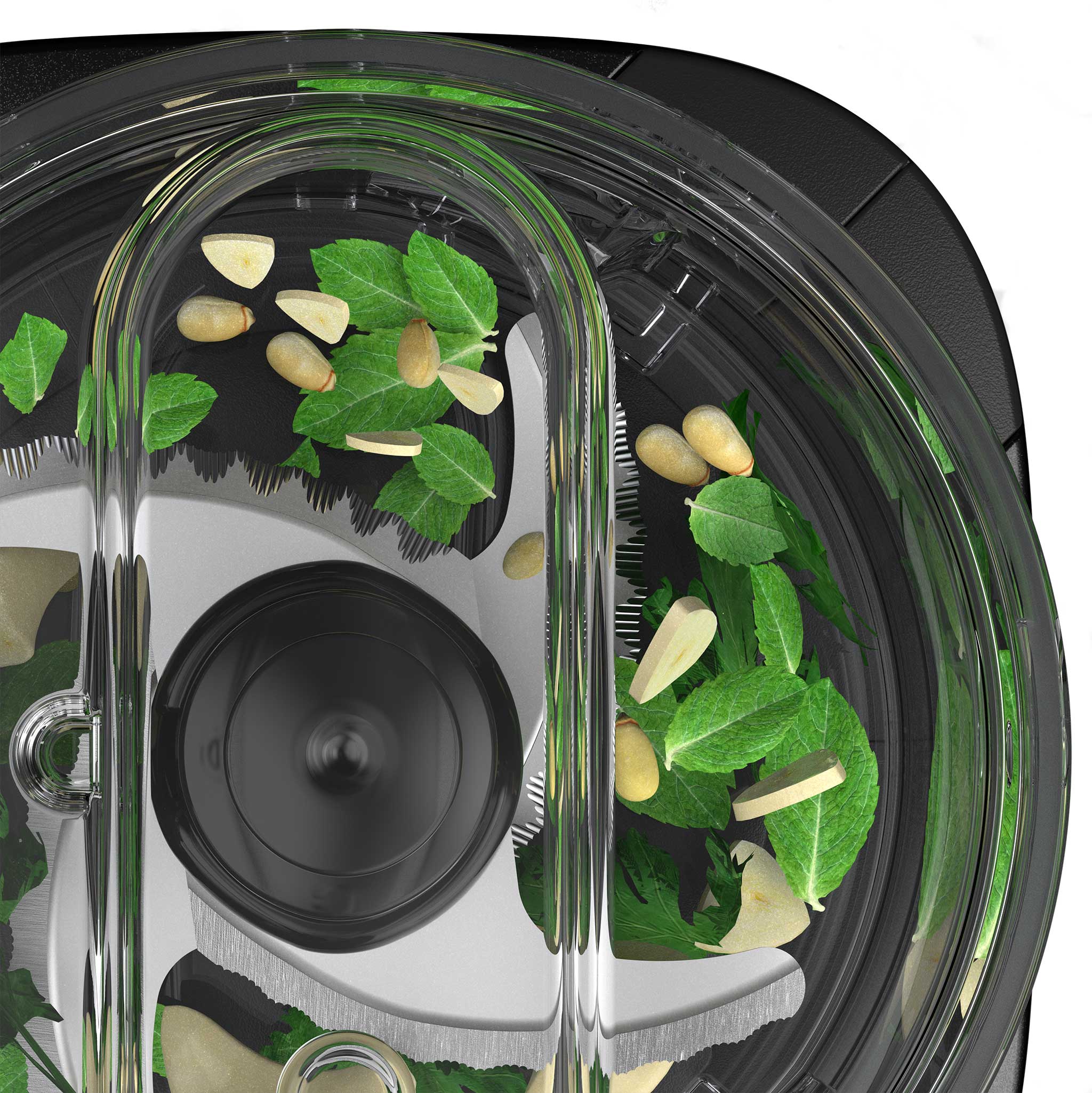 Top view of a food chopper with fresh green herbs, sliced garlic, and pine nuts inside the transparent lid and visible stainless steel blades.