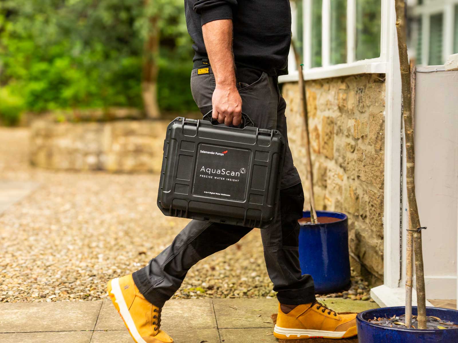 photograph of a plumber entering a domestic property carrying a tool case