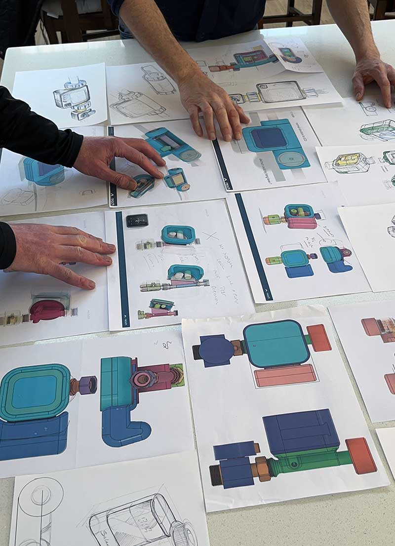 Hands showing two people evaluating design sketches of product concepts on a white table. Akin to a design review