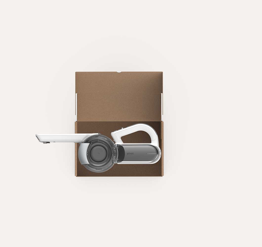Top view of a white and gray cordless handheld vacuum cleaner placed inside a brown open cardboard box on a plain light background.
