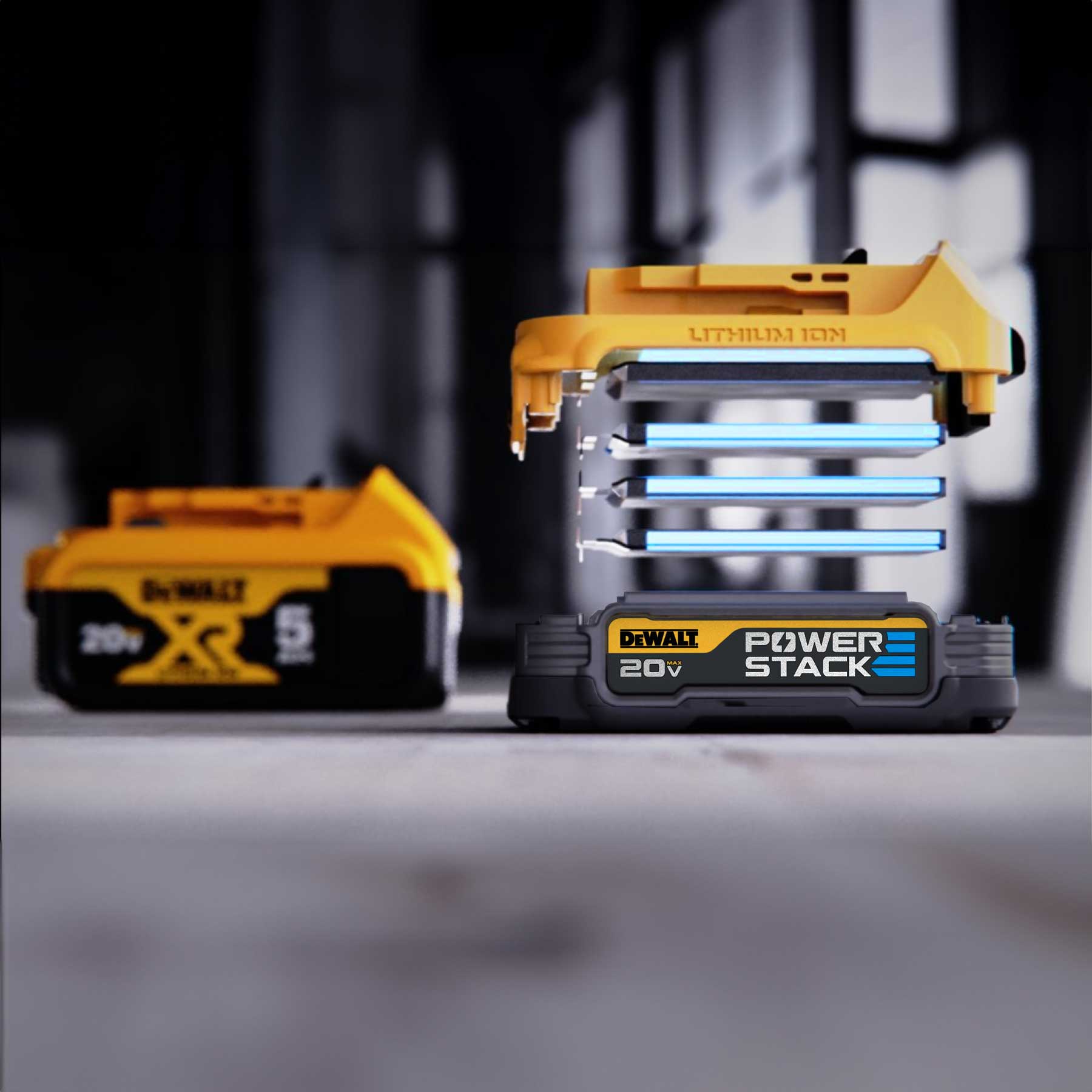 DeWalt 20V Max Powerstack lithium-ion battery shown with its layered internal structure visible, next to a second similar battery on a gray surface with a blurred industrial background.