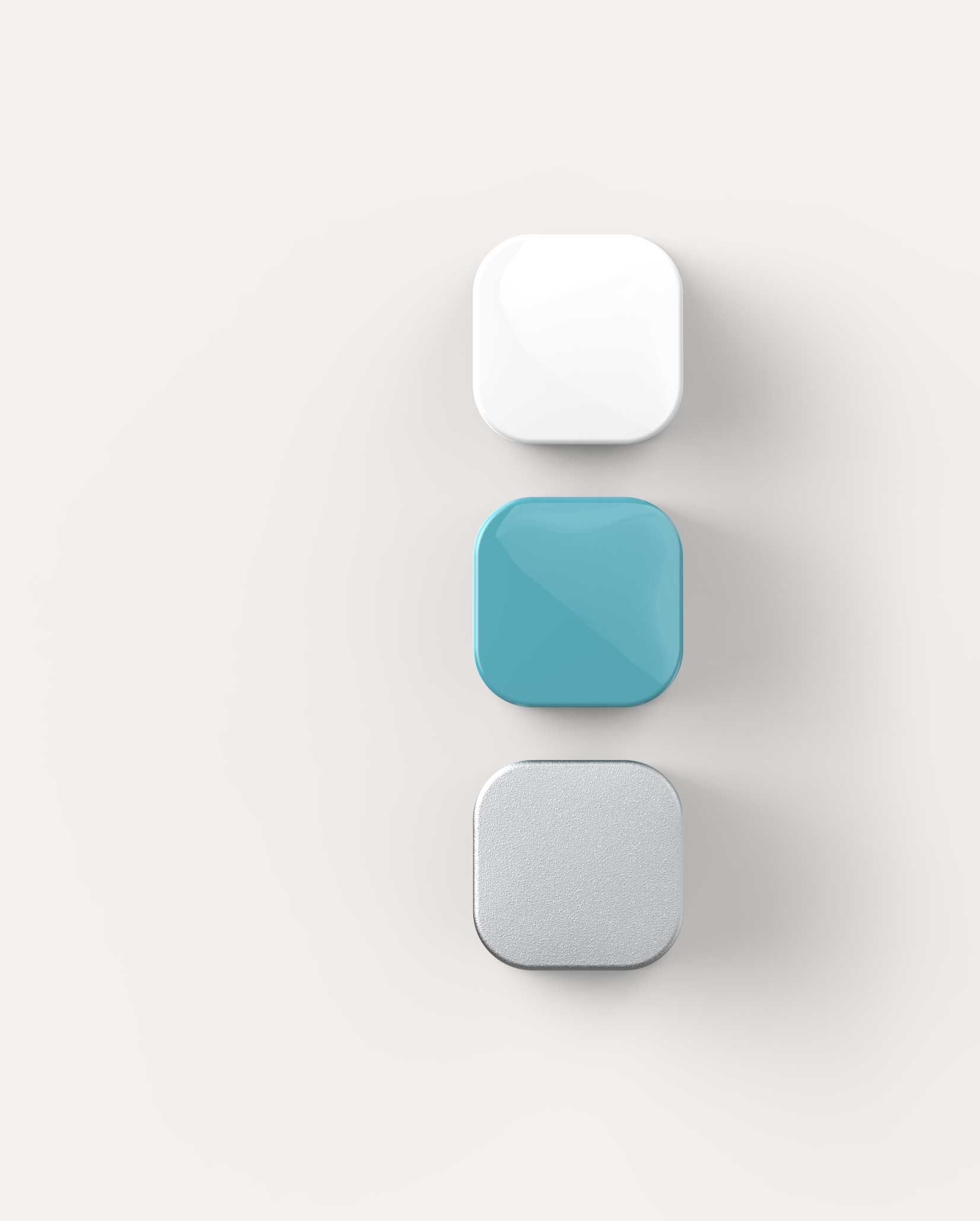 Three square-shaped blocks with rounded edges sat on the page: white glossy top, teal glossy middle, and textured silver bottom on a neutral background.