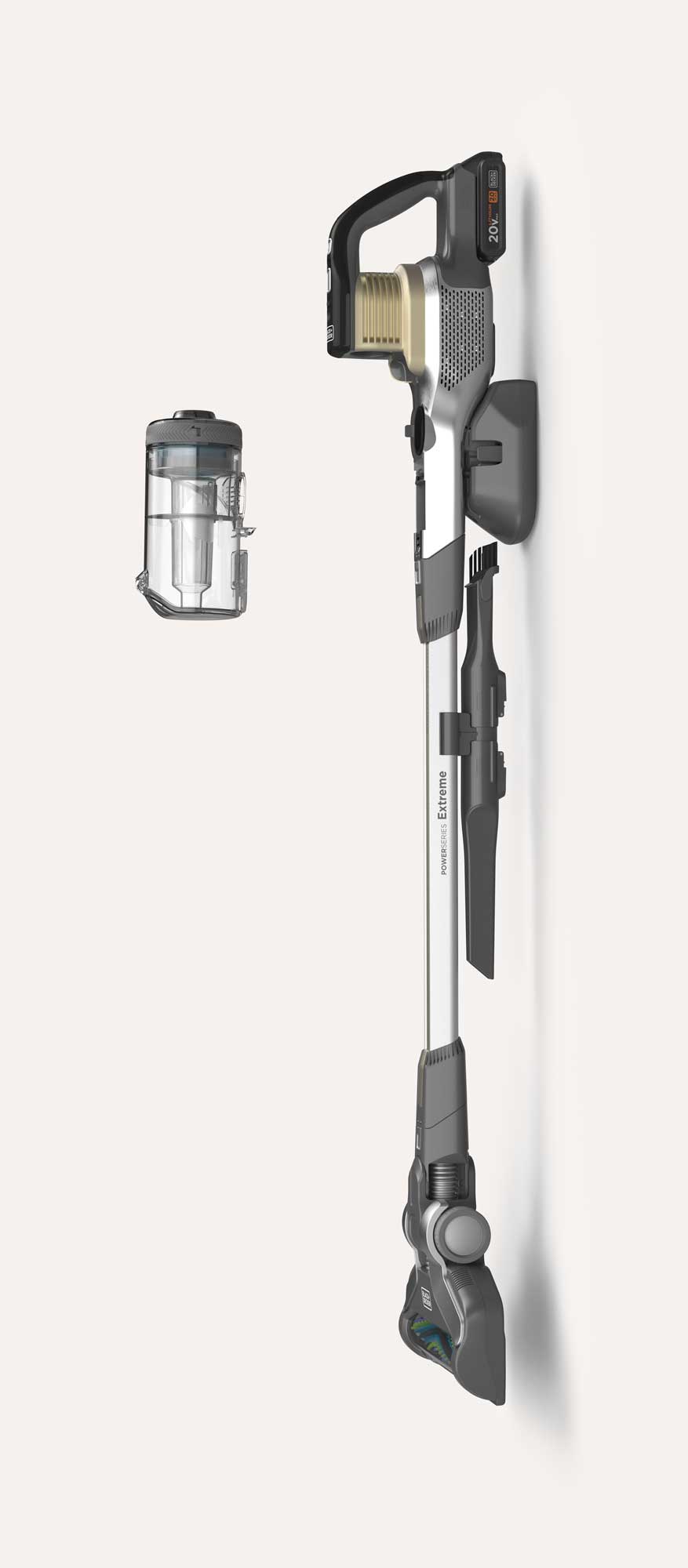 Wall-mounted cordless stick vacuum cleaner with detachable transparent dust container beside it, showing attachments on the vacuum's shaft and a 20V battery on top.