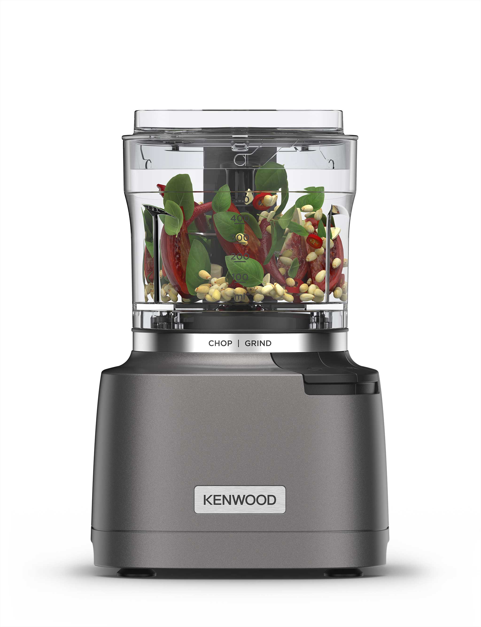 Kenwood kitchen appliance with transparent container holding chopped parsley, pine seeds and garlic, labelled with Chop and Grind options.