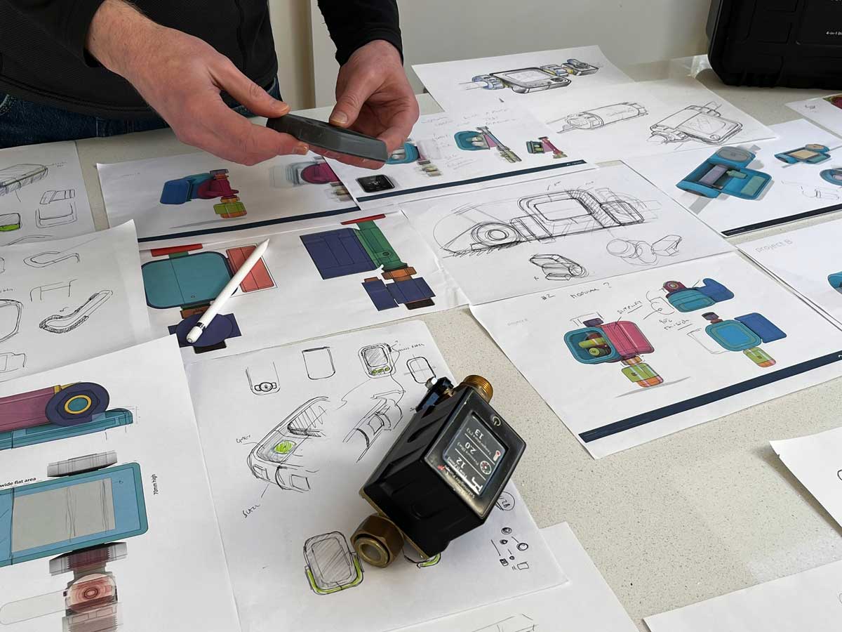 Hands showing evaluating design sketches of product concepts on a white table. Akin to a design review.