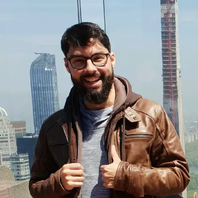 Portrait d'un homme barbu à lunettes en veste de cuir, gratte-ciel en arrière-plan, Sylvain Bouttier