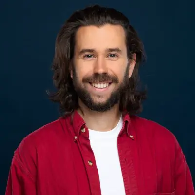 Portrait d'un homme souriant en chemise rouge sur fond bleu foncé