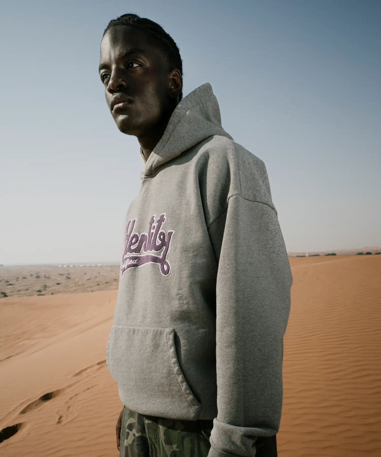 Ibo Ouro-Bodi im grauen Hoodie der Certified Identity Signature Collection vor der Wüstenlandschaft.