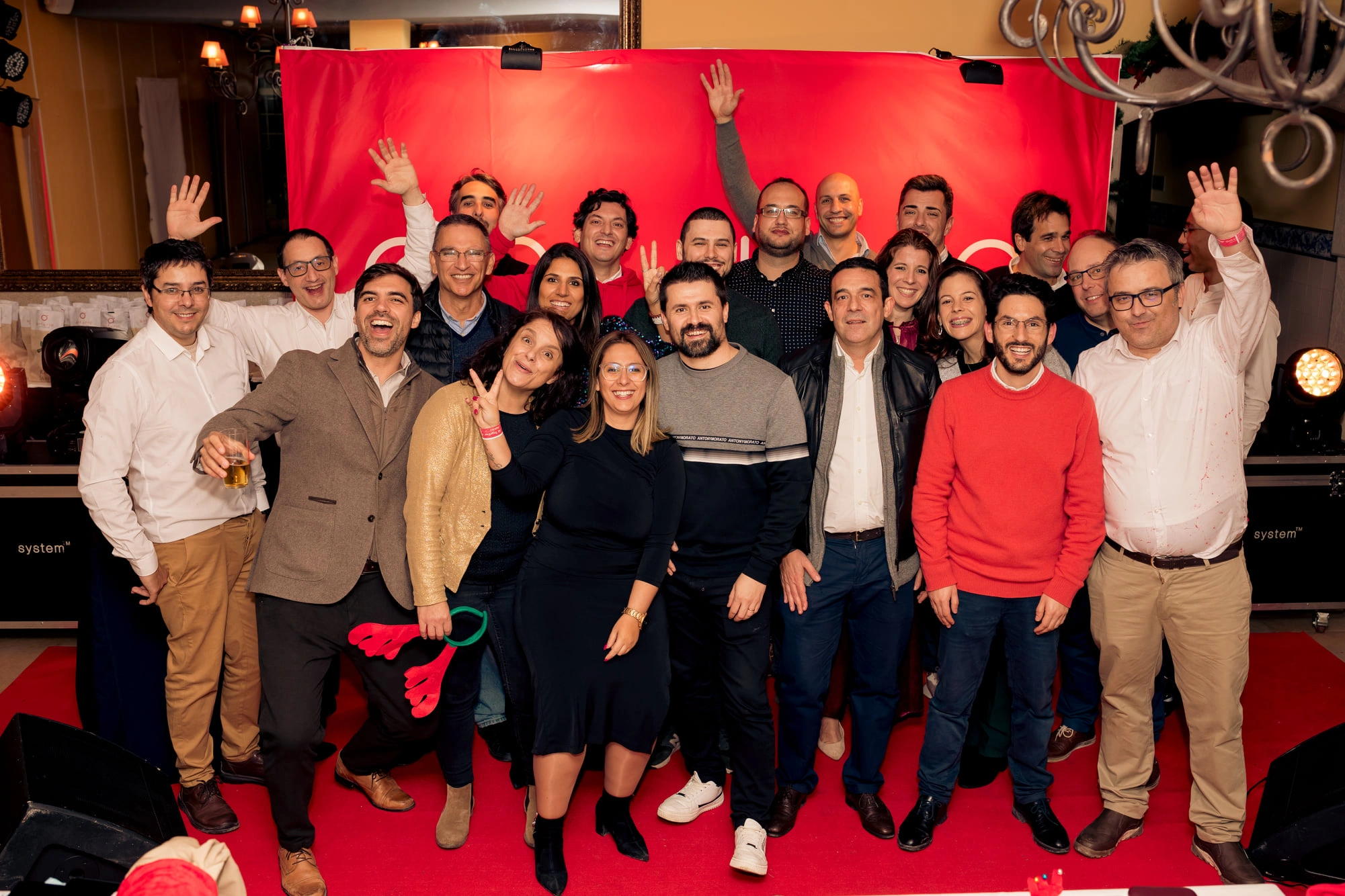 um grande grupo do anturio personele posando para uma fotografia em frente a um cenário de evento
