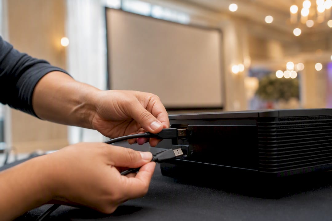 Hands changing cables on projector equipment