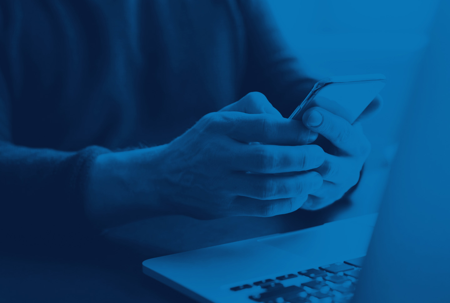 Person using a smartphone beside a laptop, representing mobile and multilingual AI chatbots for South African customers.