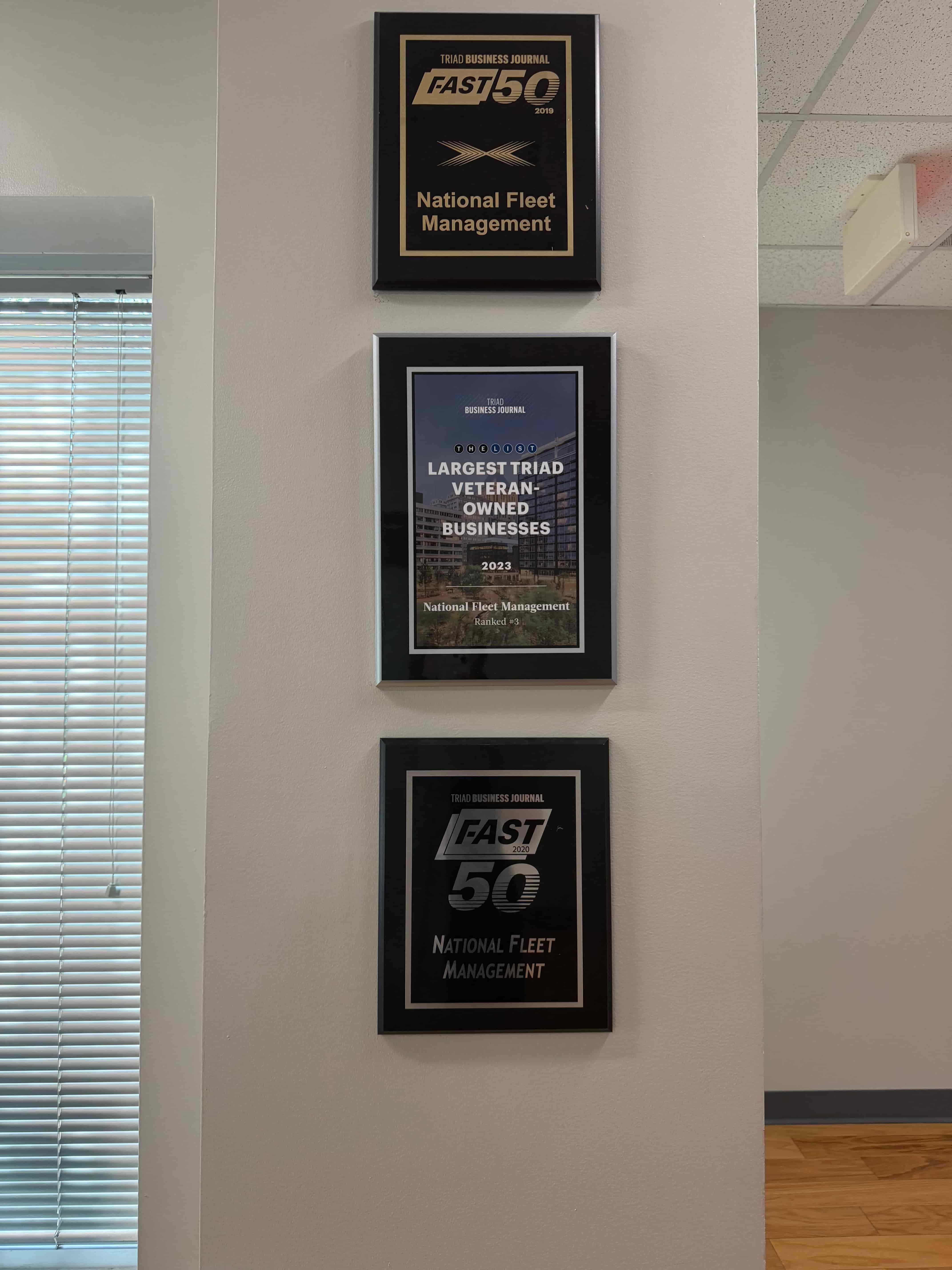 Fleet service awards displayed on office wall, including “FAST 50” and “Largest Triad Veteran-Owned Businesses 2023” for National Fleet Management