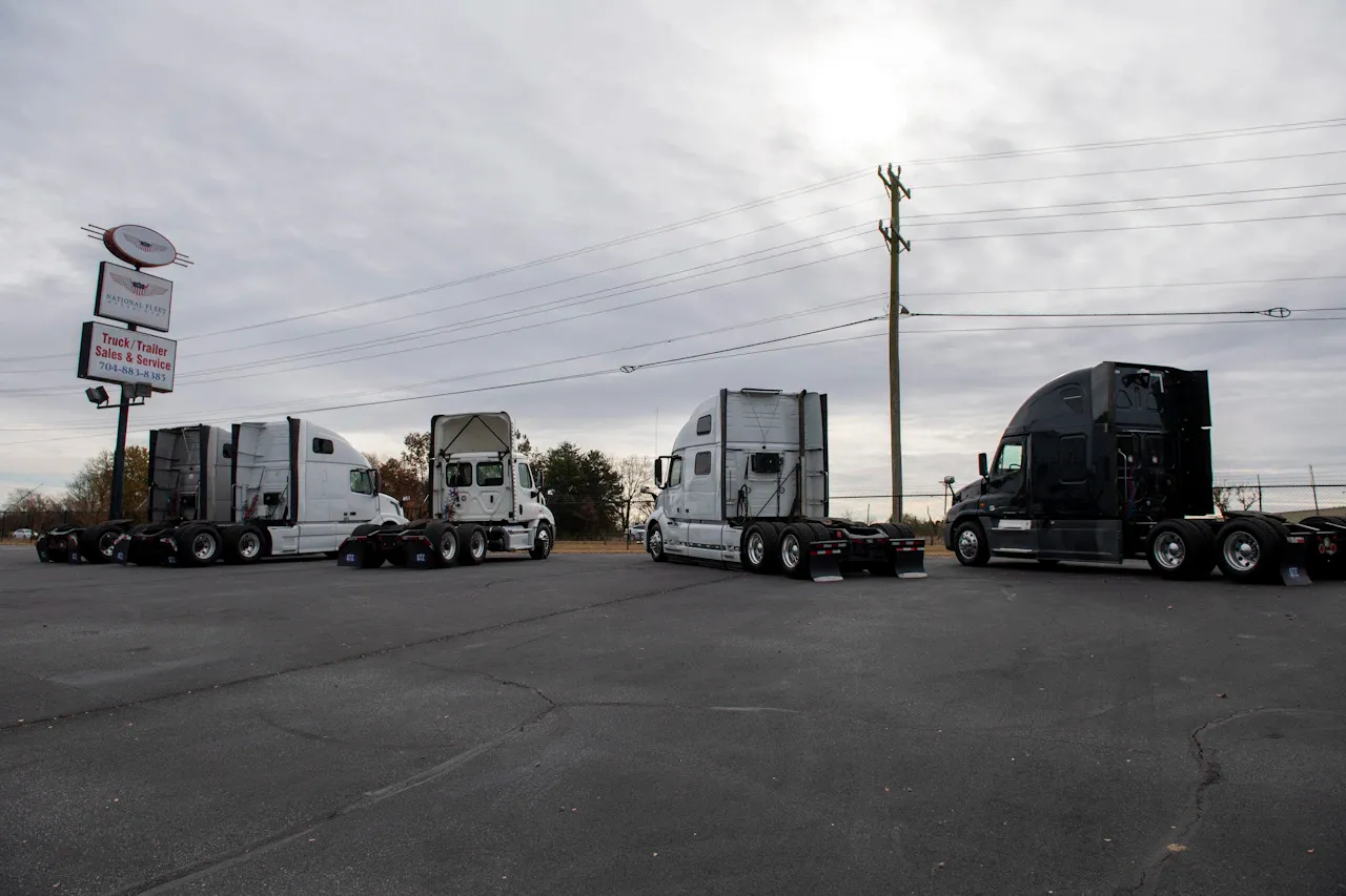 Fleet maintenance service with semi trucks lined up in lot near “Truck & Trailer Sales & Service” sign for heavy-duty repair.
