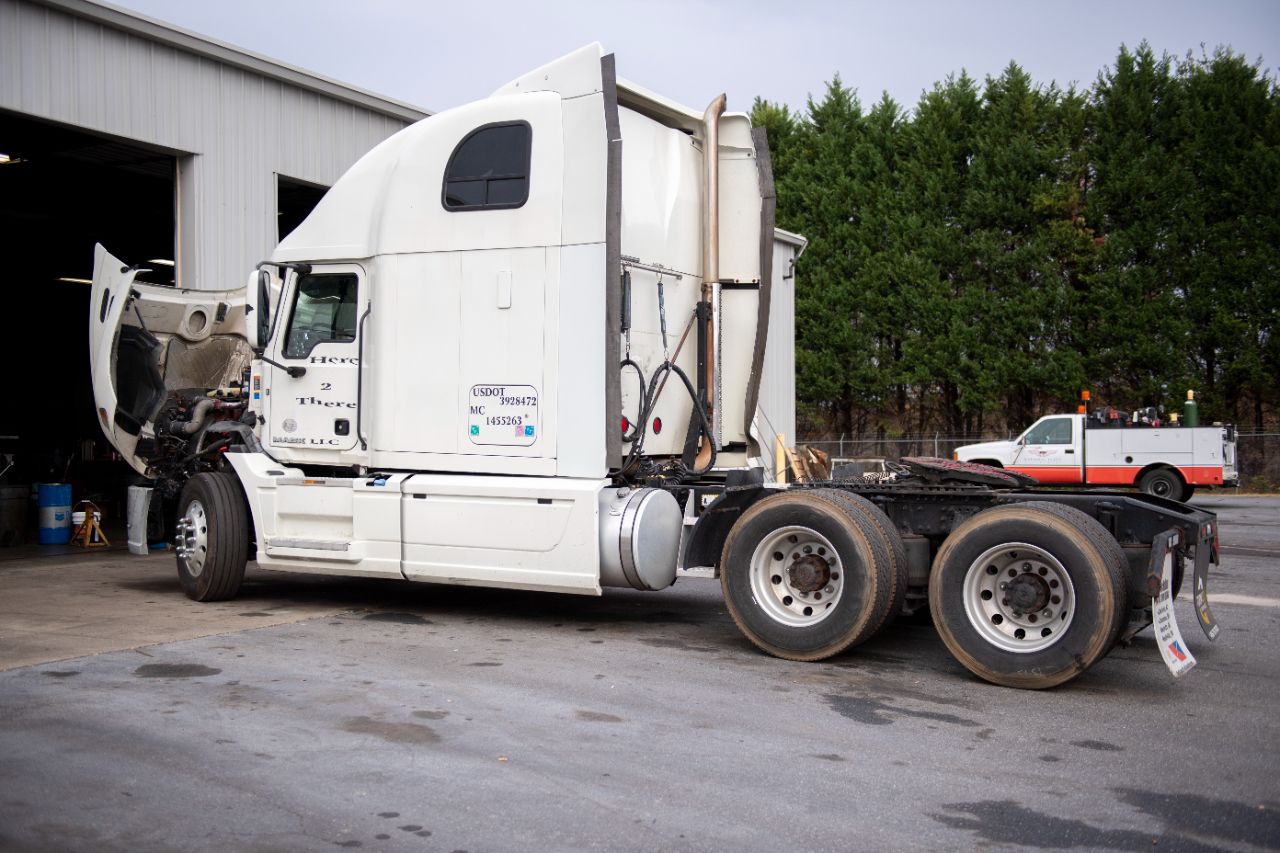 Scheduled maintenance for a heavy-duty semi-truck parked beside a roadside service vehicle.