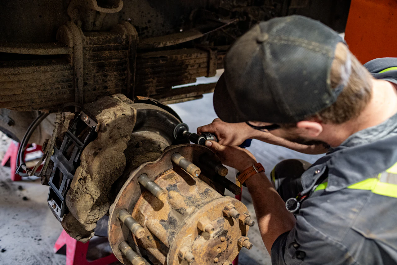 Technician performing heavy-duty brake rotor repair on a truck axle assembly.