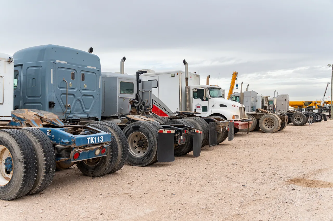 Fleet of heavy-duty trucks lined up in a service yard, ready for maintenance and repair.