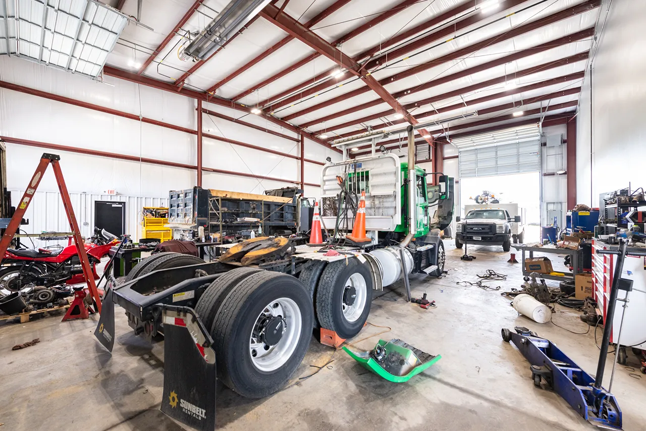 Fleet services bay with a heavy-duty truck undergoing repair among tools, lifts, and service equipment.