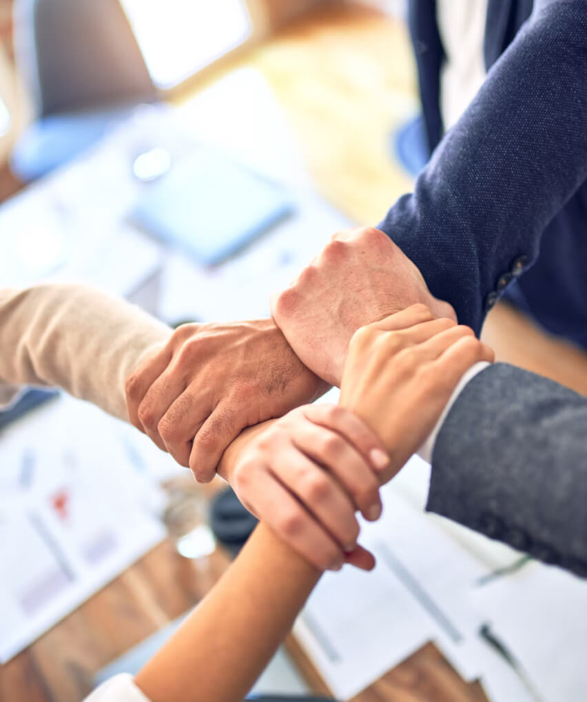 Team members joining hands together symbolizing trust, unity, and strong partnership in a business environment.