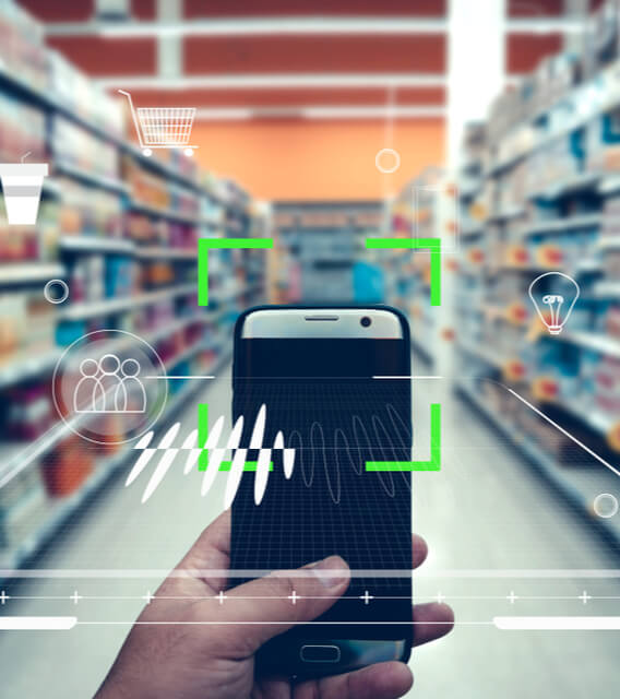 Person using smartphone to scan retail products in a supermarket aisle, symbolizing eCommerce technology and digital retail innovation.