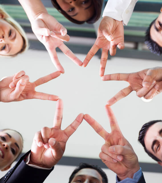 A diverse group of professionals forming a star shape with their fingers while smiling and looking down, symbolizing teamwork and exciting career opportunities at TRANSFORM Solutions.
