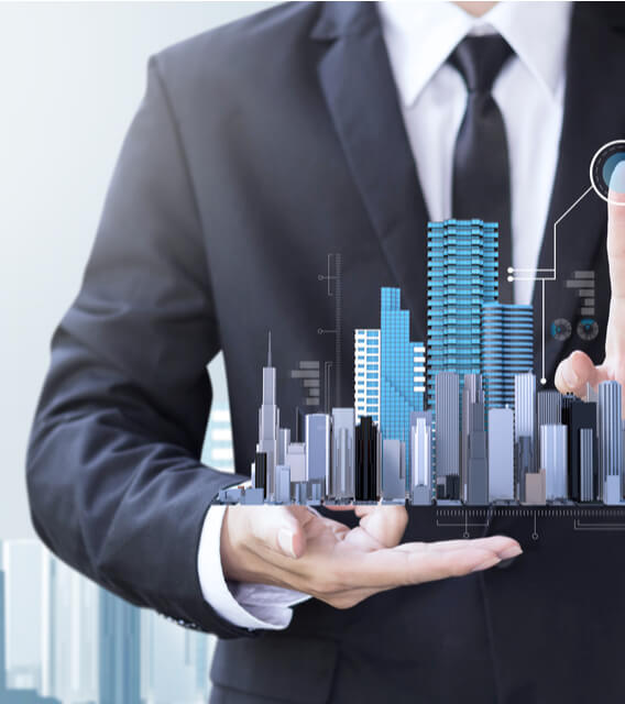Businessman holding a 3D model of city skyscrapers representing real estate management, property investment, and urban development.