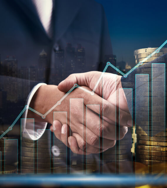 Two business professionals shaking hands with financial growth charts and stacked coins overlayed, symbolizing partnership and business success.