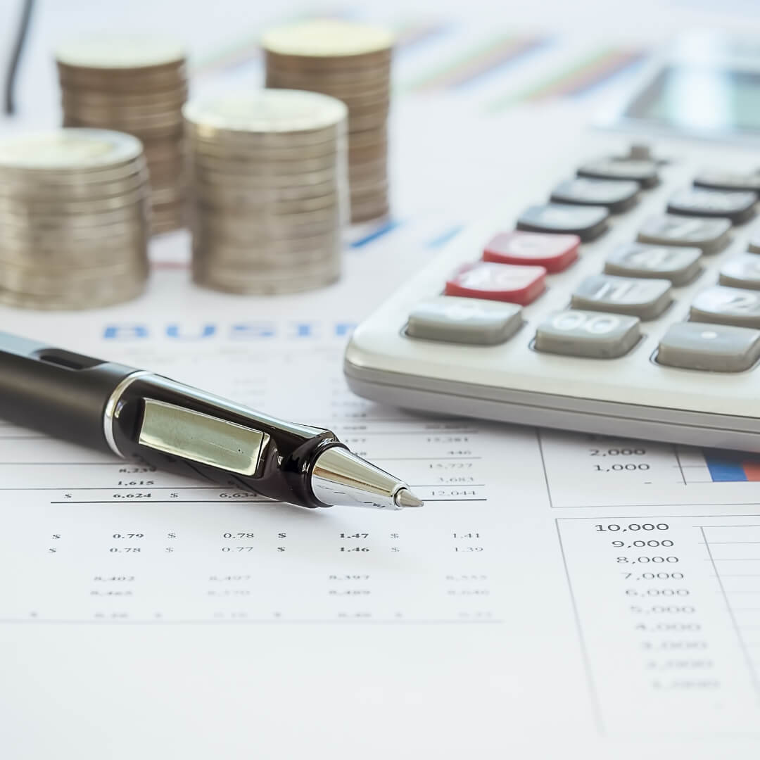 Stacks of coins, a calculator, and a pen on financial documents symbolizing mutual fund analysis, investment growth, and financial planning services.
