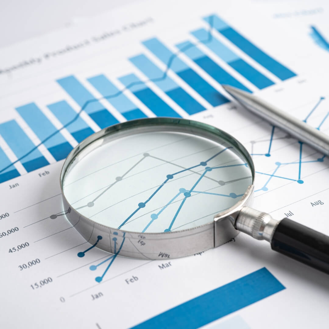 Magnifying glass focusing on financial charts and bar graphs, symbolizing data research and analytical support for private equity and venture capital.