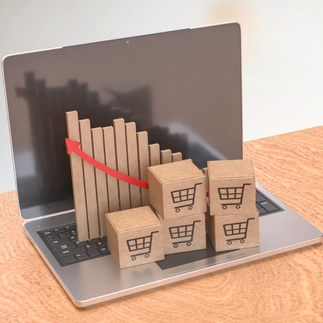 Cardboard boxes with shopping cart icons stacked on a laptop beside an upward graph, symbolizing eCommerce operations and online retail growth.