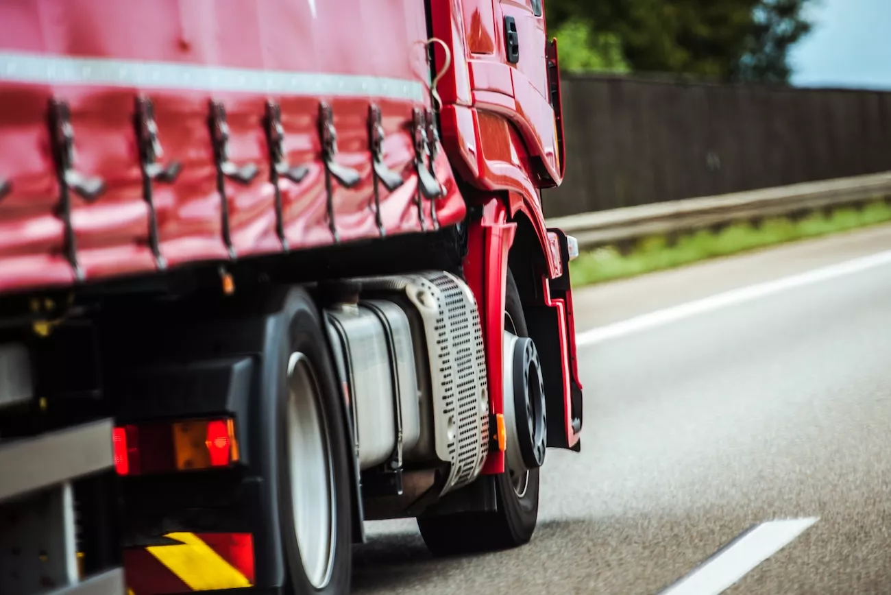 Red truck with full truck load on the motorway.