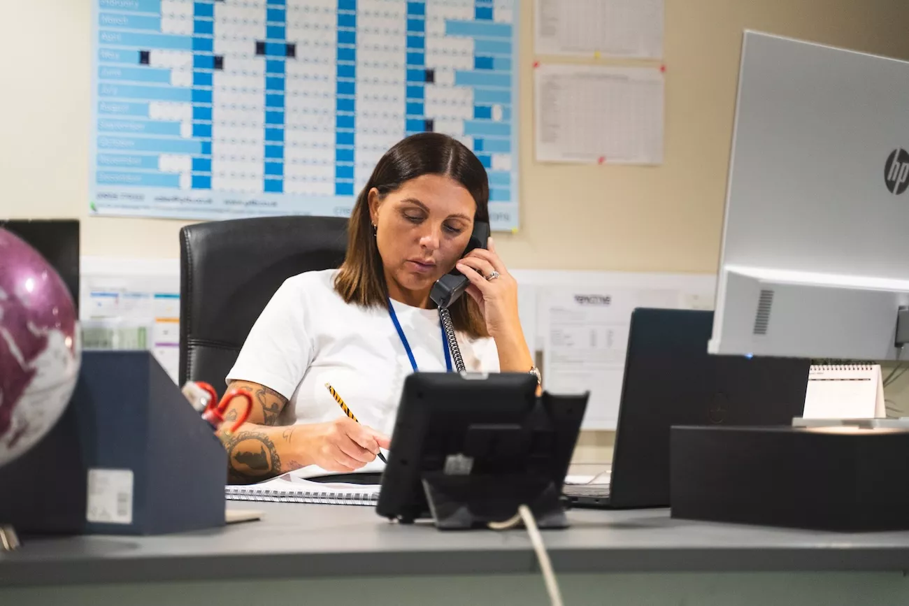 AMW Couriers logistics coordinator handling a customs clearance enquiry by phone at her desk