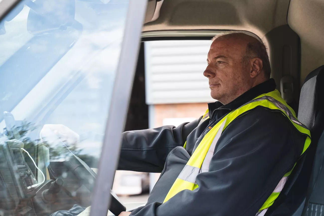 Professional AMW Couriers driver in hi-vis vest at the wheel of a specialist delivery vehicle