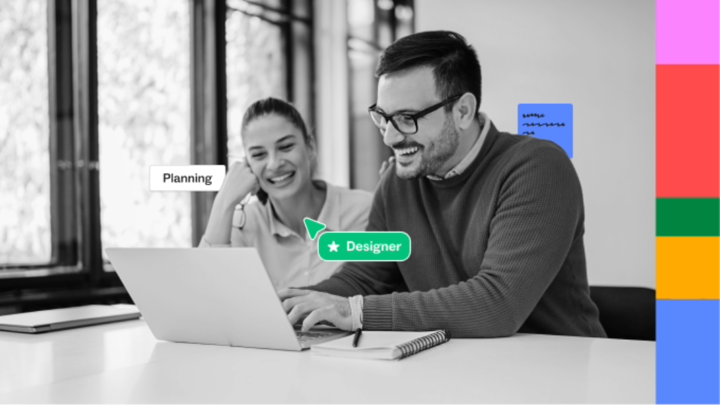 Two people sitting at a desk looking at a laptop