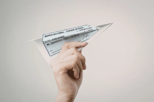 Cheque de pago doblado como avión de papel, imagen del riesgo de aceptar cheques al vender un auto u